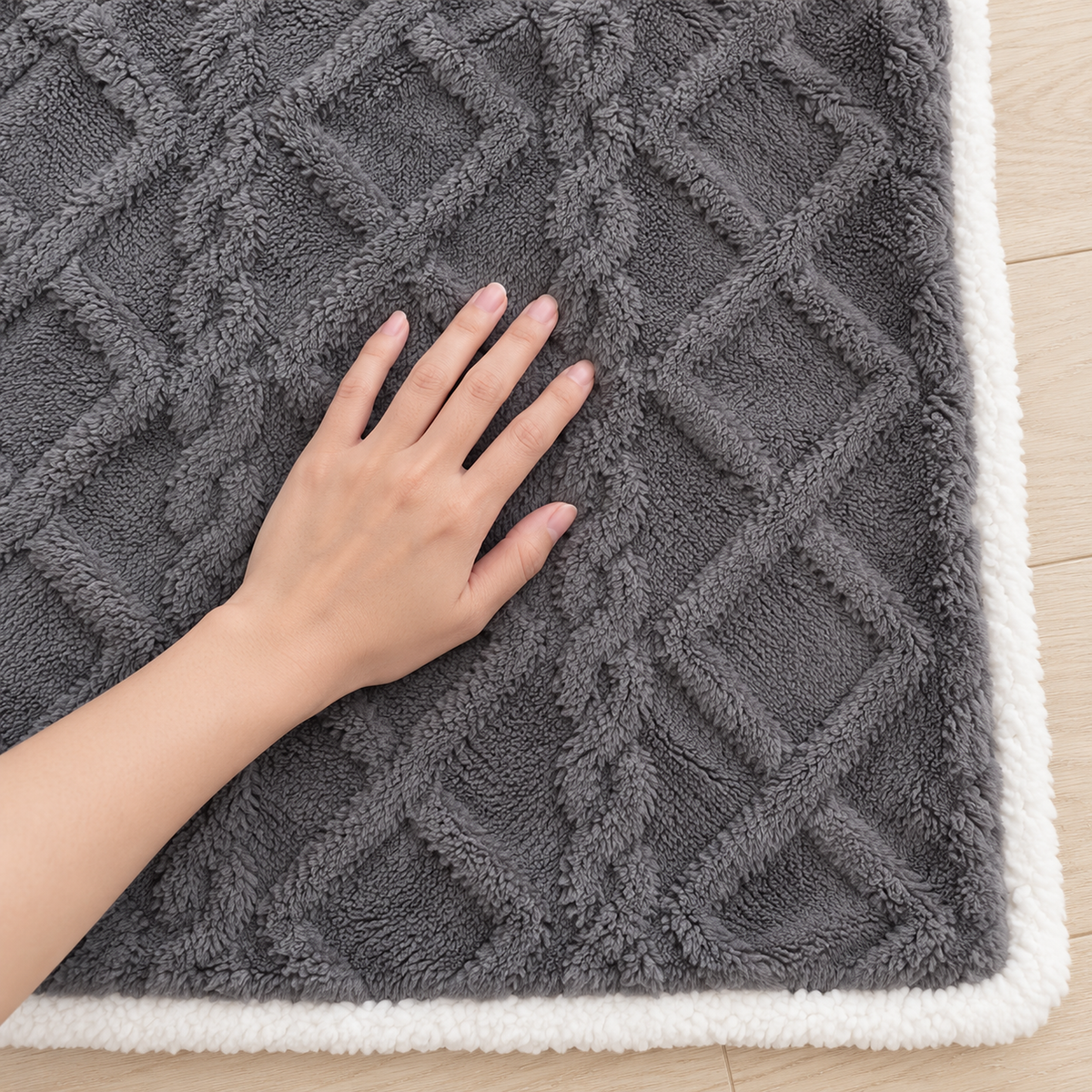 Mosilen charcoal and white soft throw blanket with a hand gently pressing its textured face on a pale floor