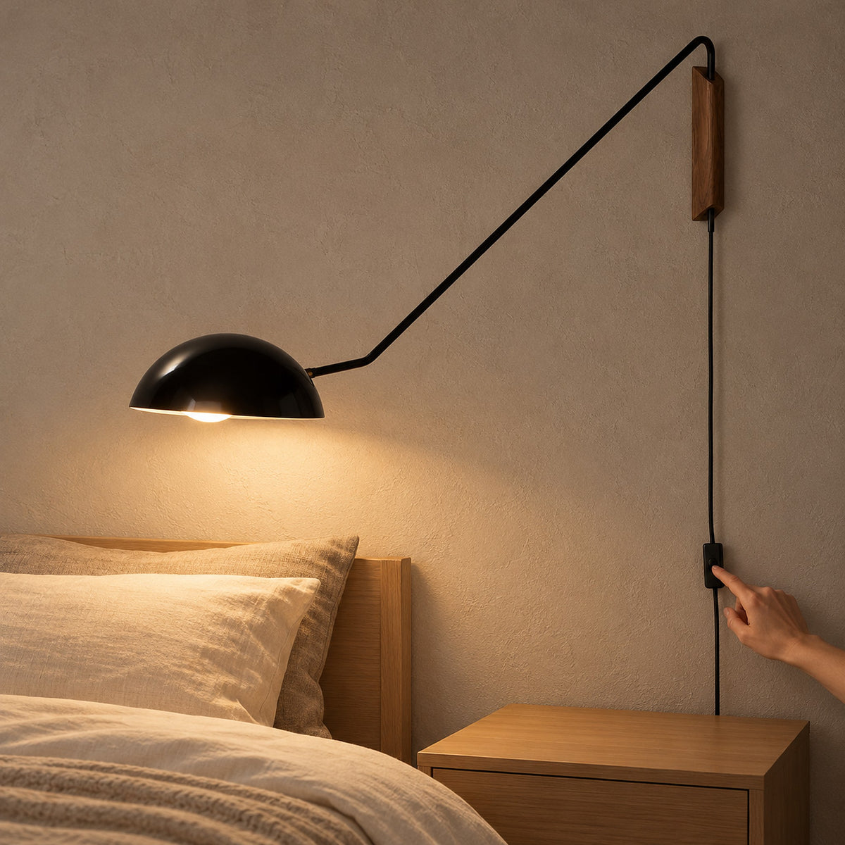 Nalesio black plug in wall light lit as a hand reaches for the inline switch on the cord