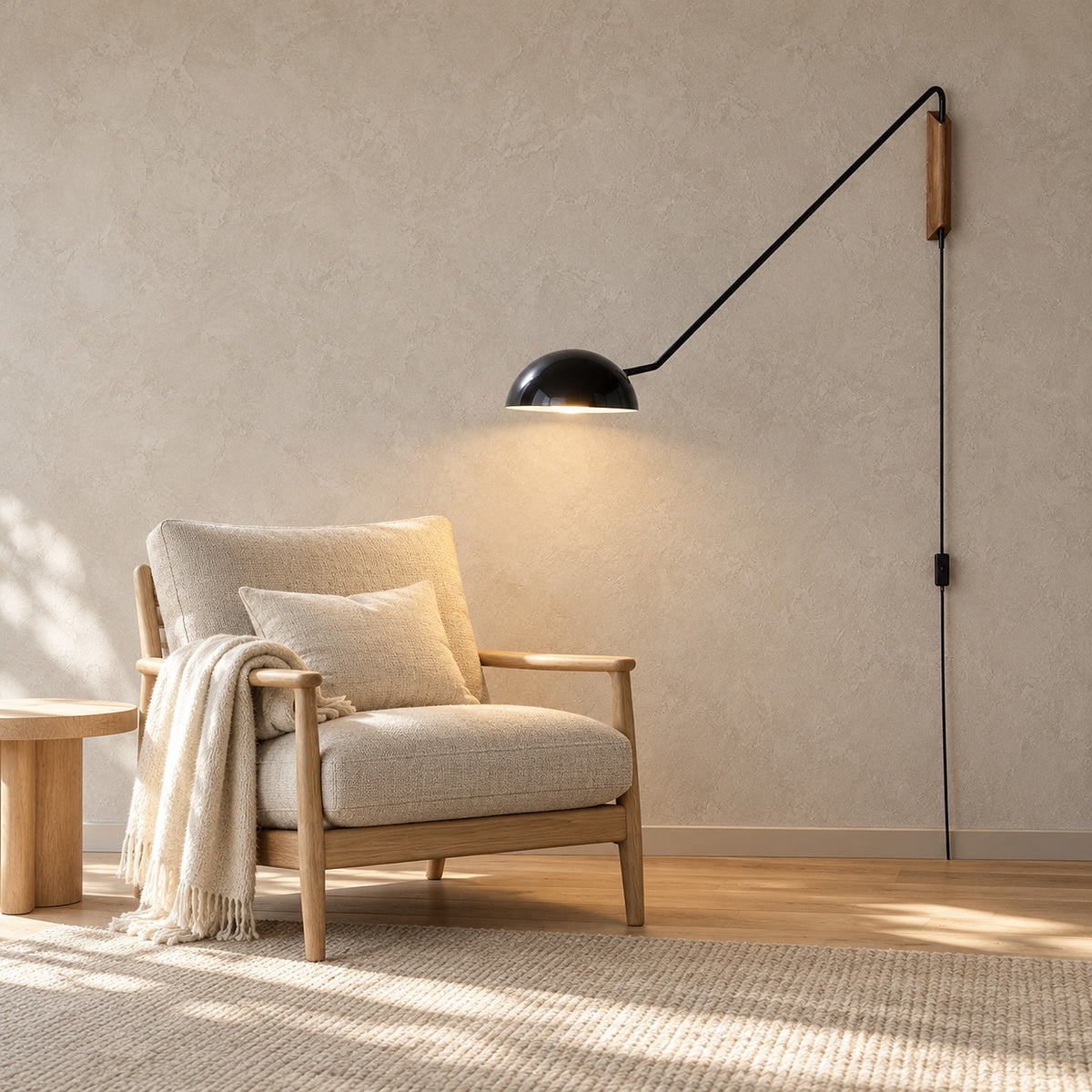Nalesio black wall sconce lit beside an armchair on a plain plaster living room wall