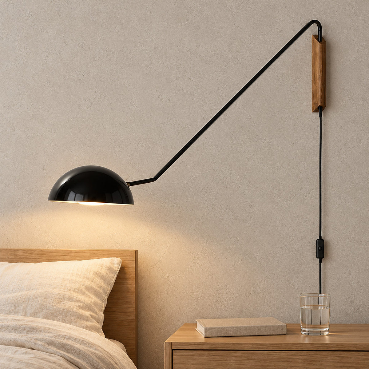 Nalesio black wall sconce switched on with warm light over a clear guest bedside in daylight