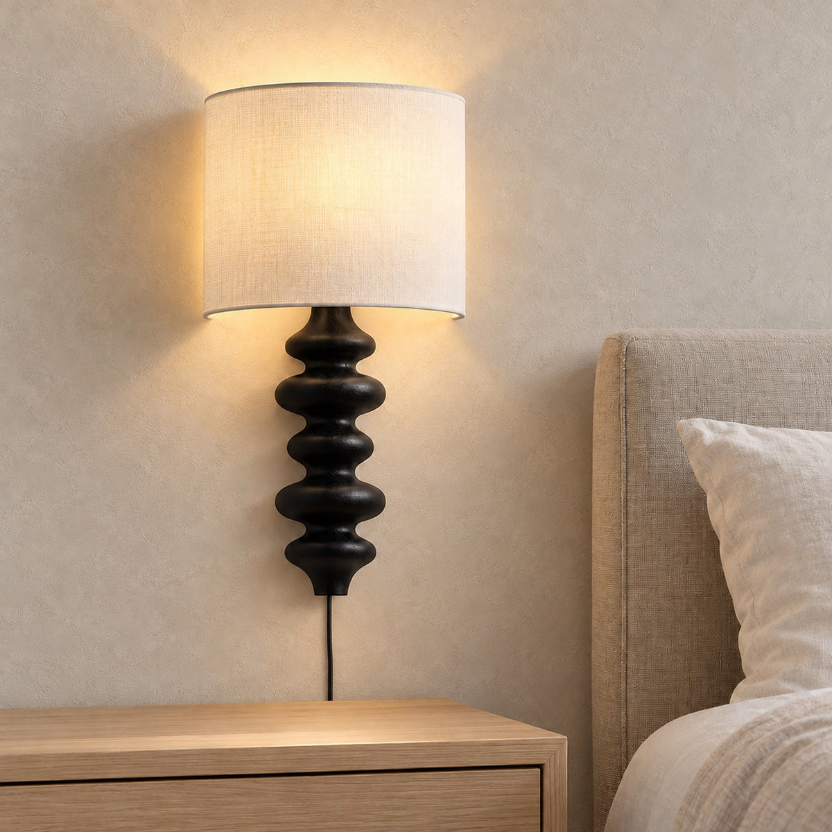Nalimor black bedside wall light glowing above a clear nightstand in a guest bedroom