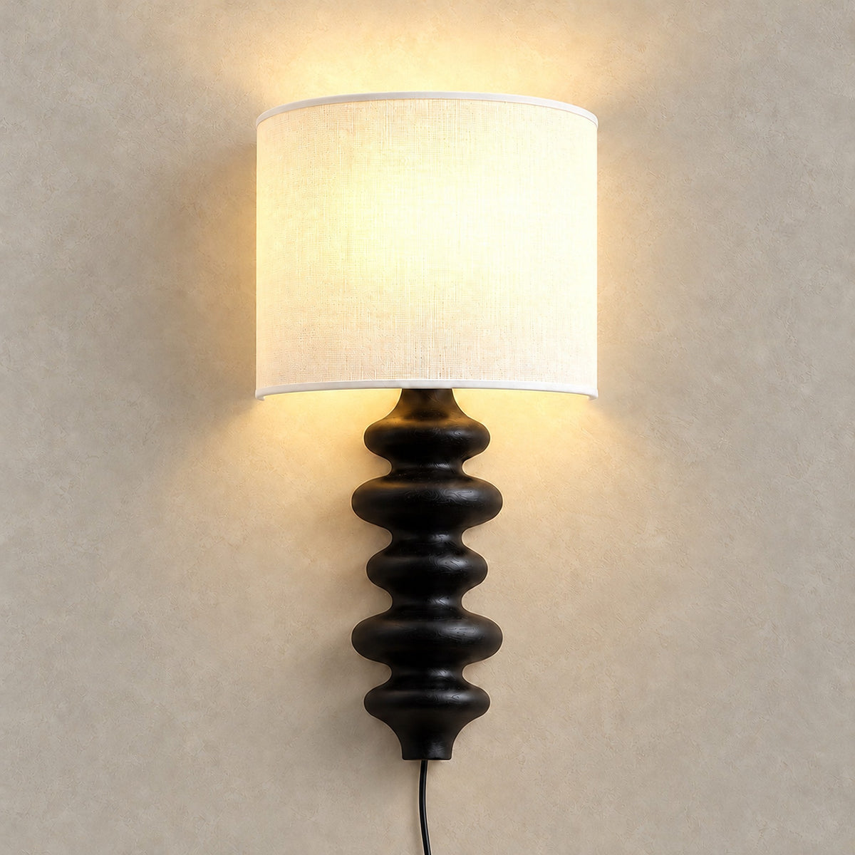 Nalimor black plug in wall lamp glowing softly against greige plaster