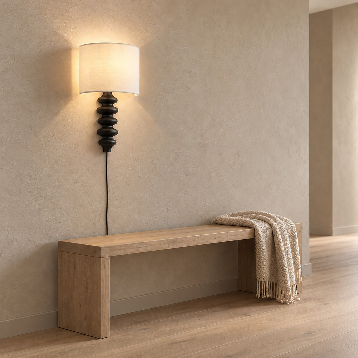 Nalimor black wall sconce lit above a hallway bench during the day