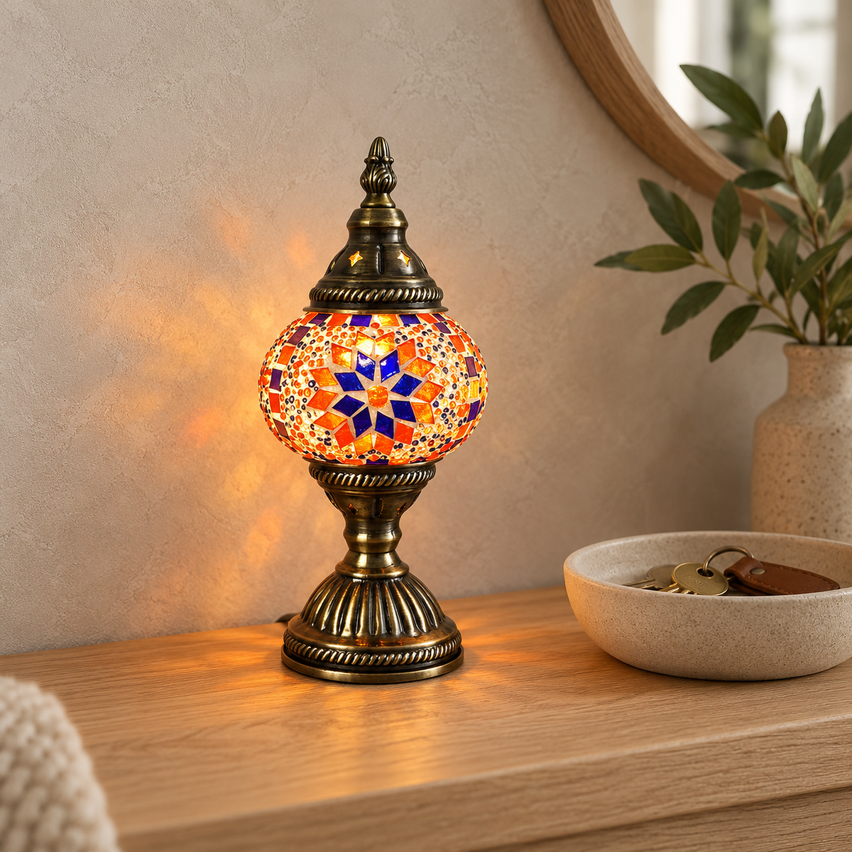 Nalvesa table lamp in a light bronze finish glowing on an entryway console, its colored glass mosaic globe lit by day