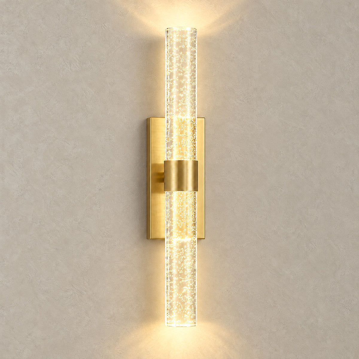 Nimarlo gold LED wall sconce glowing above and below, casting upward and downward light on the wall