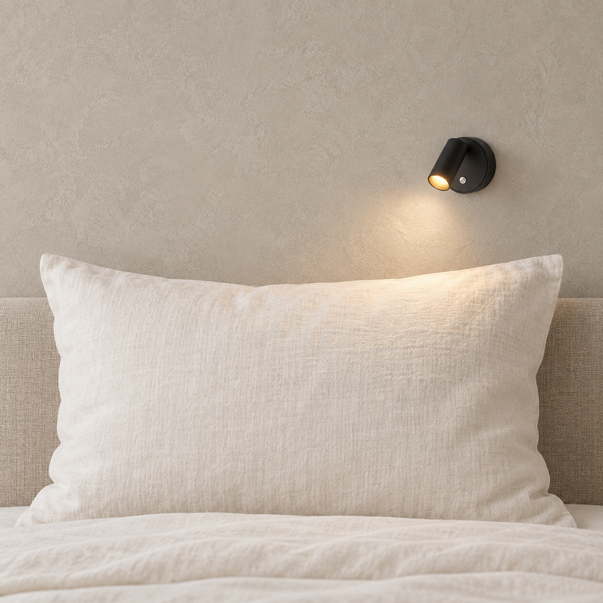 Nocarel black bedside lamp casting warm light onto a full pillow in a bright bedroom