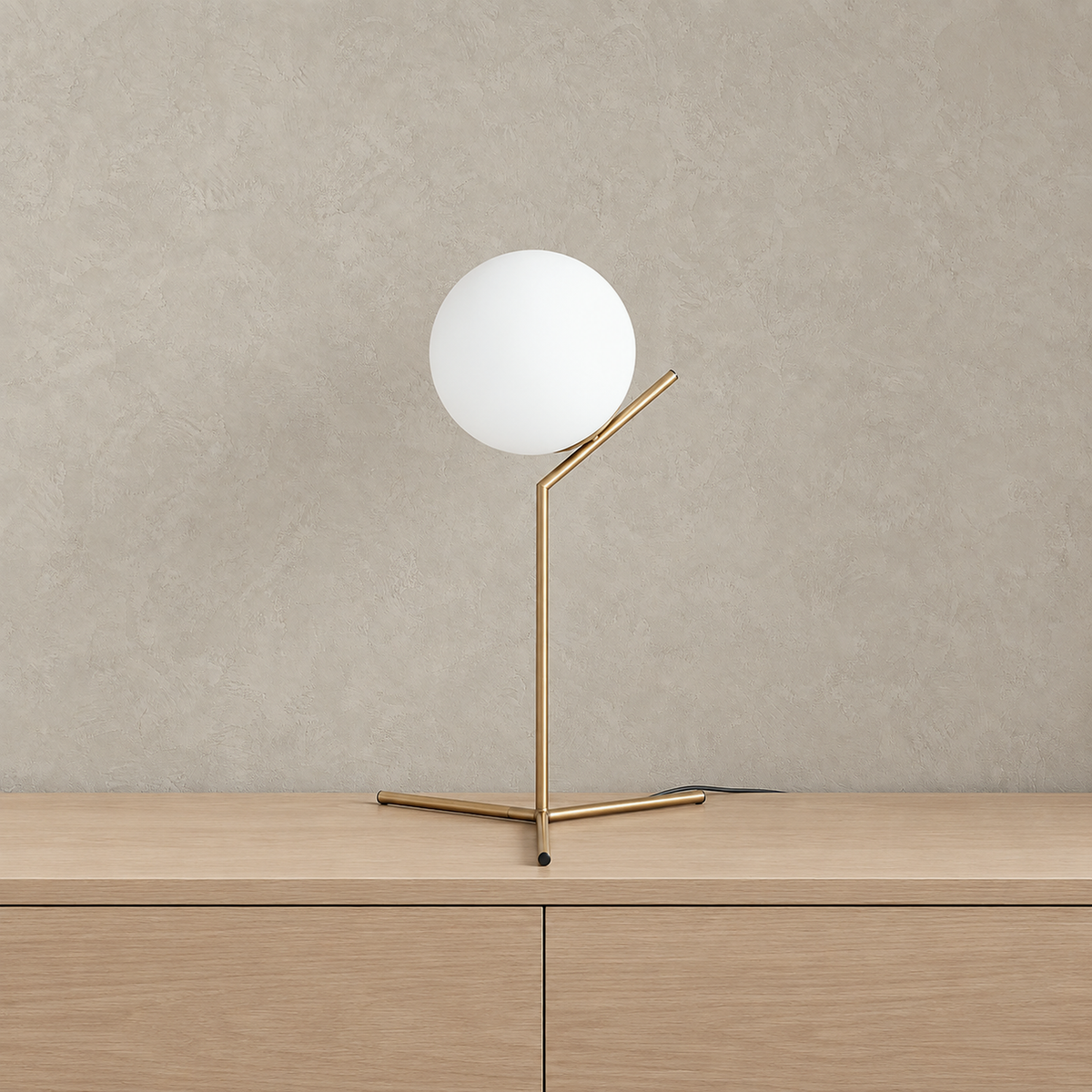 Olvarena bedside table lamp with a gold tone metal body and white spherical glass shade, unlit on a pale tabletop