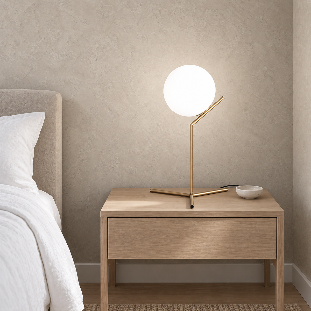 Olvarena table lamp with a gold tone body lit by day in a guest sleeping alcove, glowing through the white glass globe