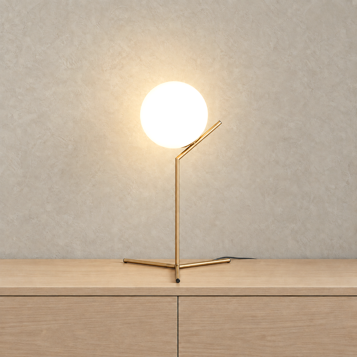 Olvarena table lamp in a gold tone finish with its white glass globe softly illuminated against a plain backdrop