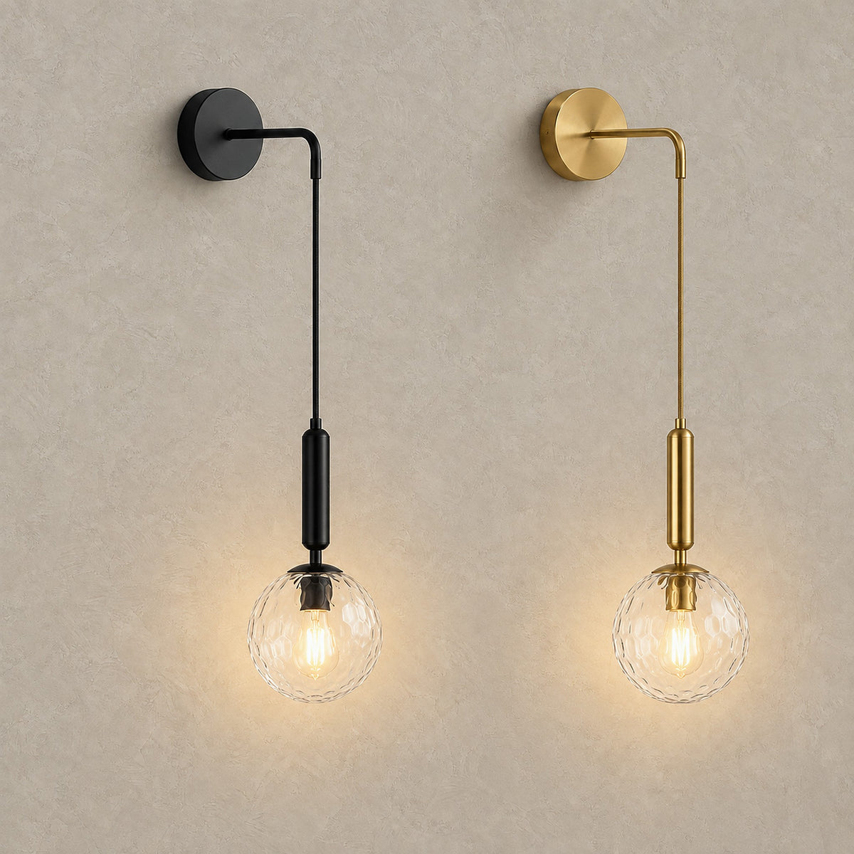 Orlamen black and gold wall sconces side by side, both glowing with clear glass globes