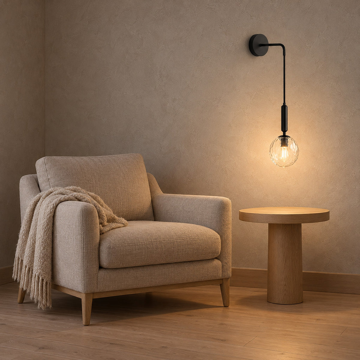Orlamen Black hardwired wall light glowing above an empty round wooden side table beside an armchair.