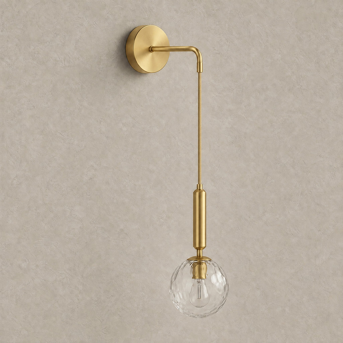 Orlamen gold hardwired wall light with clear glass globe, unlit against greige plaster #color_gold