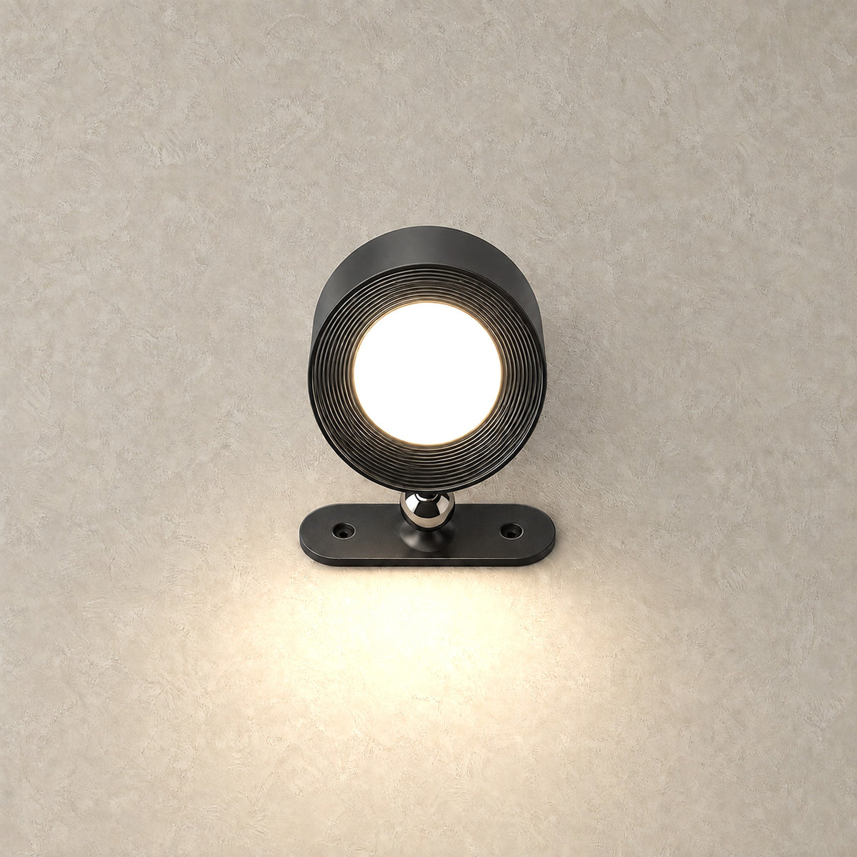 Orsilen black LED wall sconce switched on, glowing against a greige plaster wall