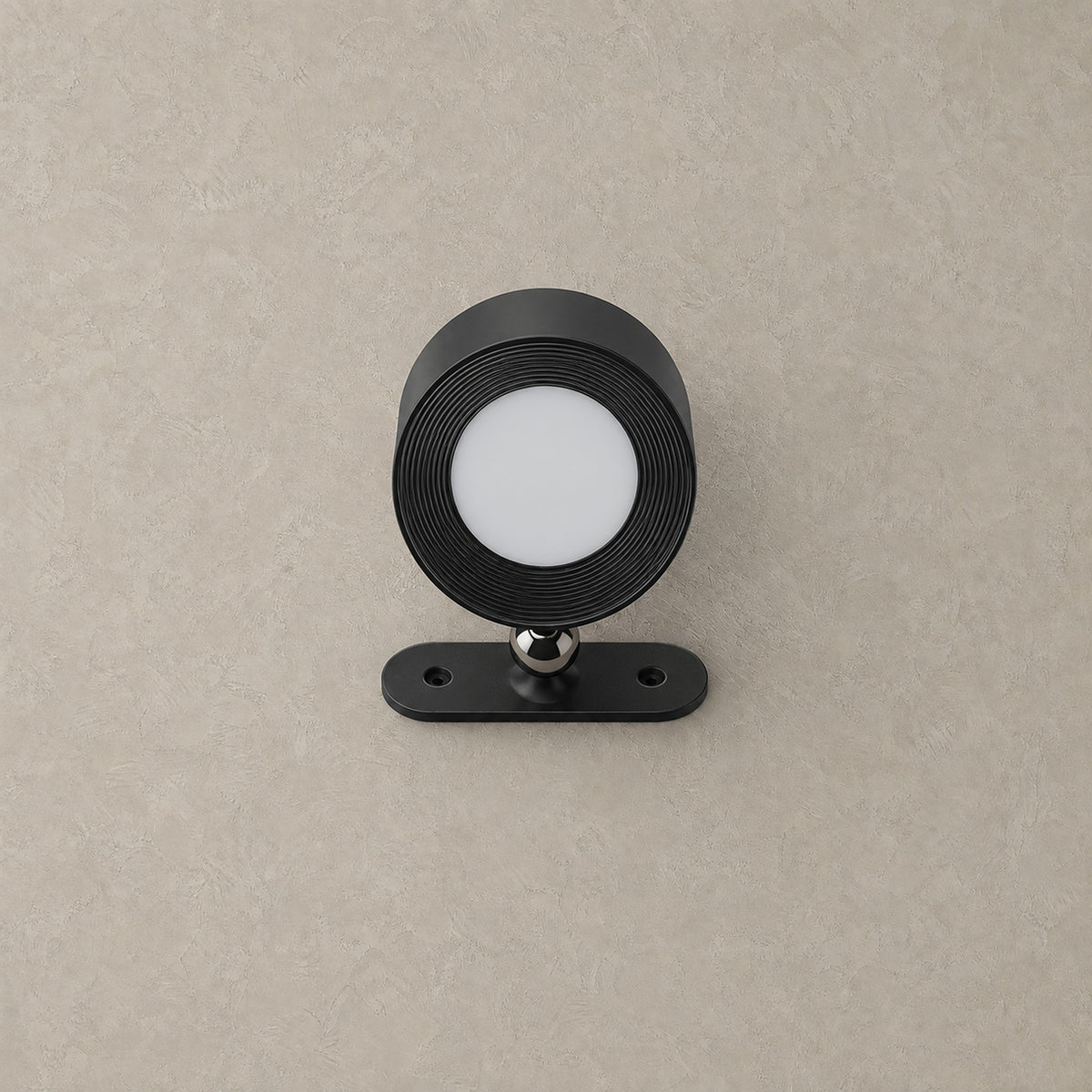 Orsilen rechargeable wall spotlight in black, shown unlit against greige plaster