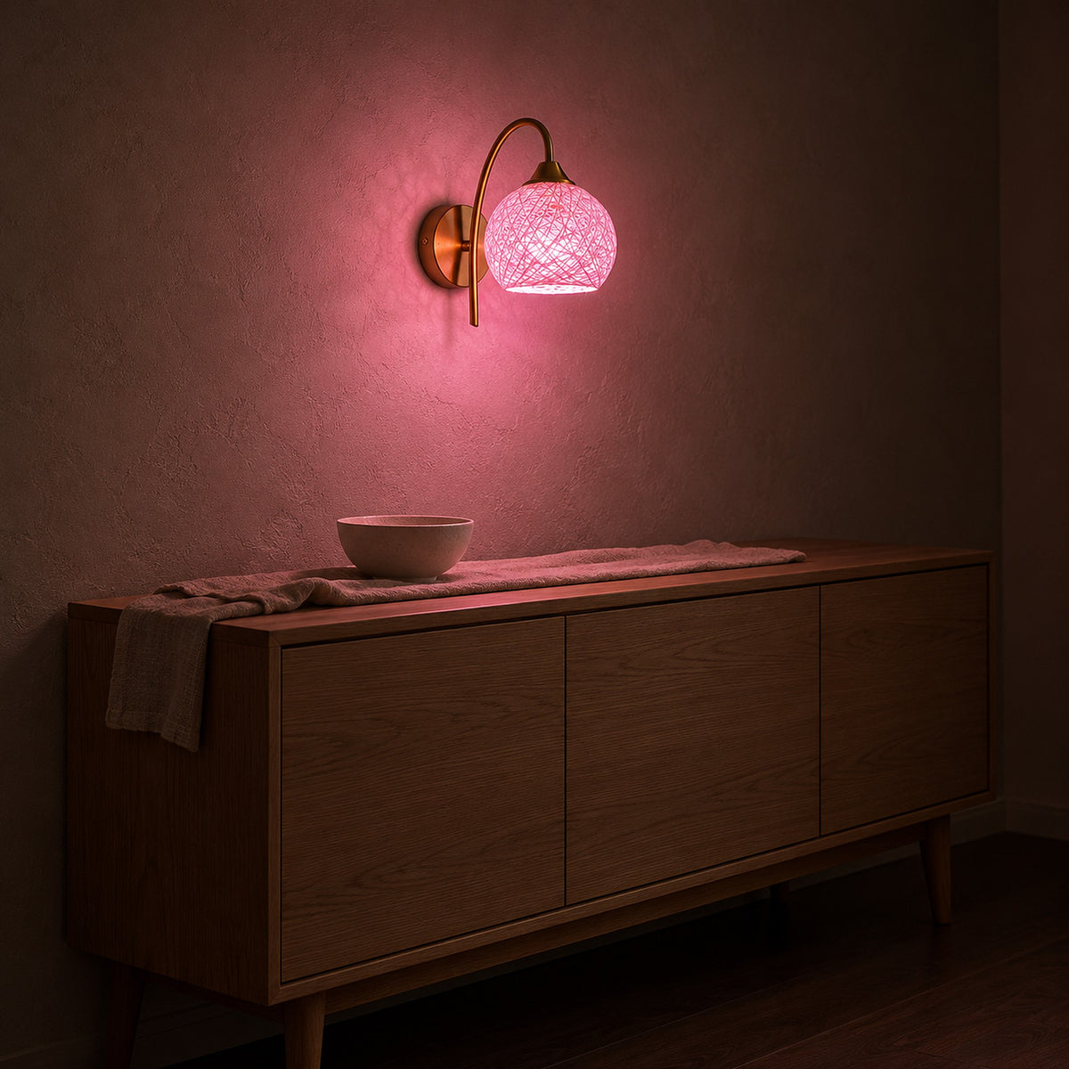 Remilvo gold wireless wall light set to a pink color mode, glowing on a dining room wall at night