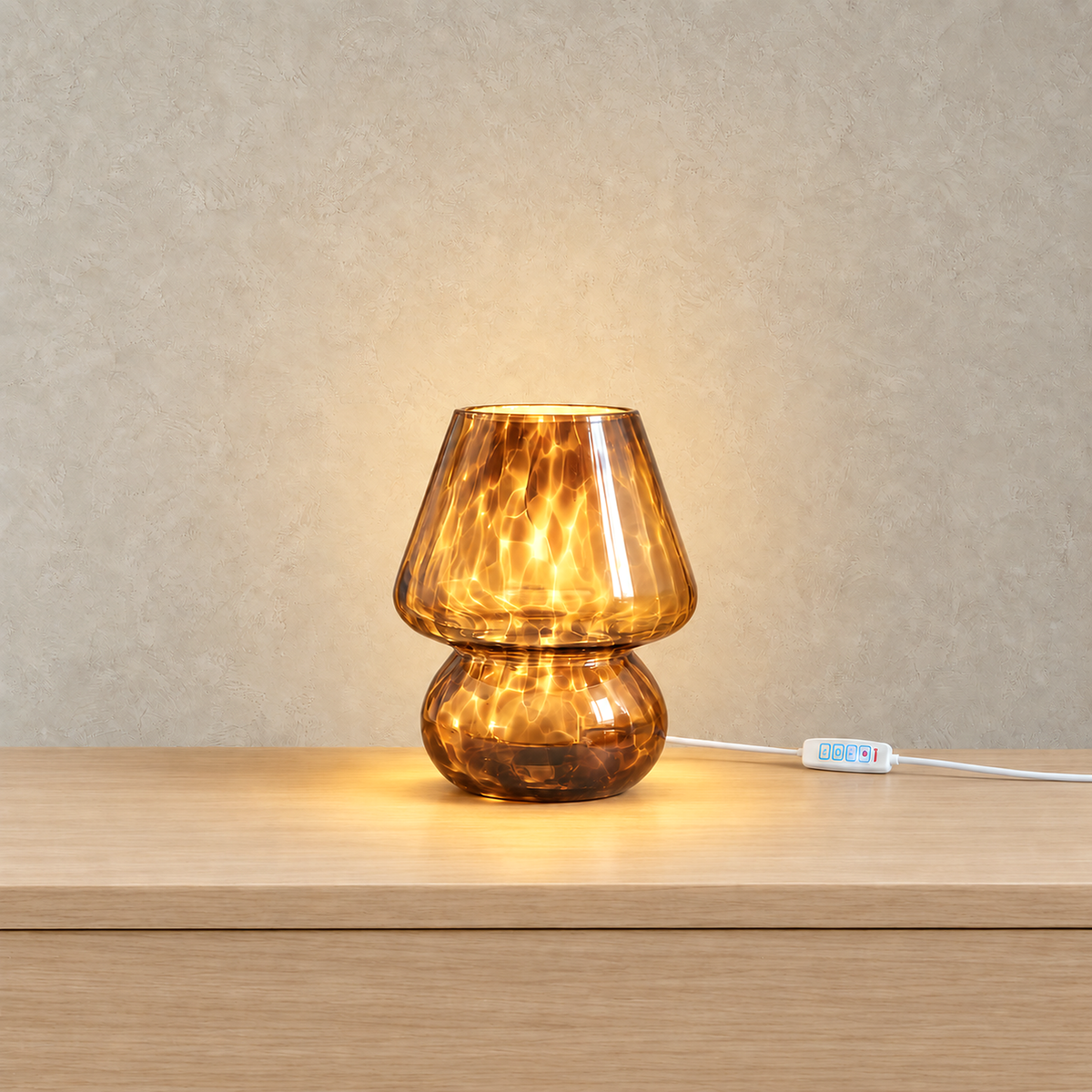 Rimelota brown mushroom table lamp switched on with the glass cap and base both lit on a plain backdrop
