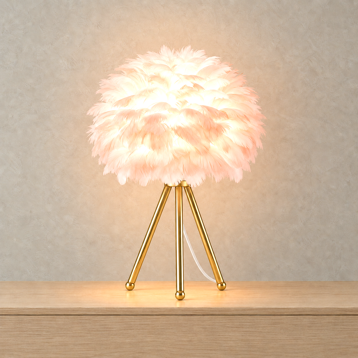 Rimolen light pink gold table lamp lit against greige plaster, light showing through the feather shade