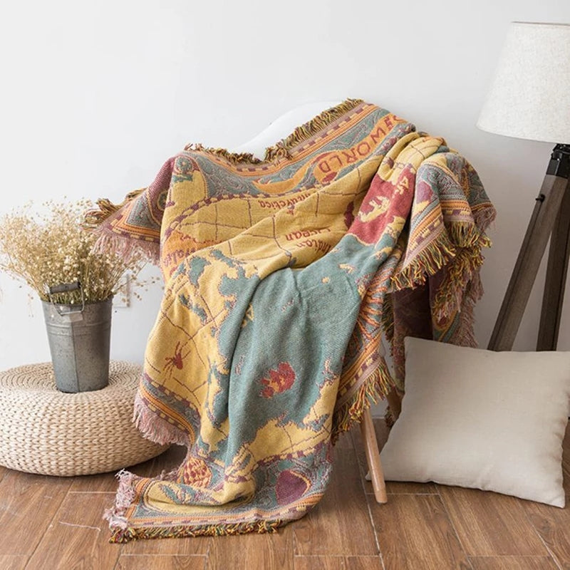 Saloveri world map throw blanket draped over a chair, showing its colorful map pattern and fringed edges.