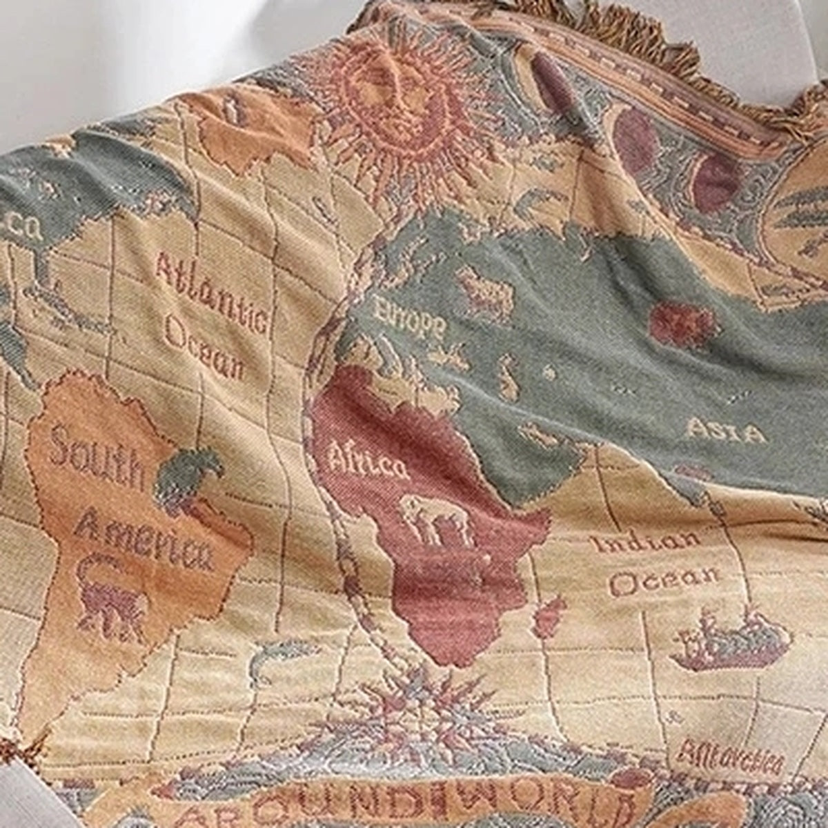 Saloveri world map throw blanket draped on a white sofa, showing Africa, Europe, Asia and South America.