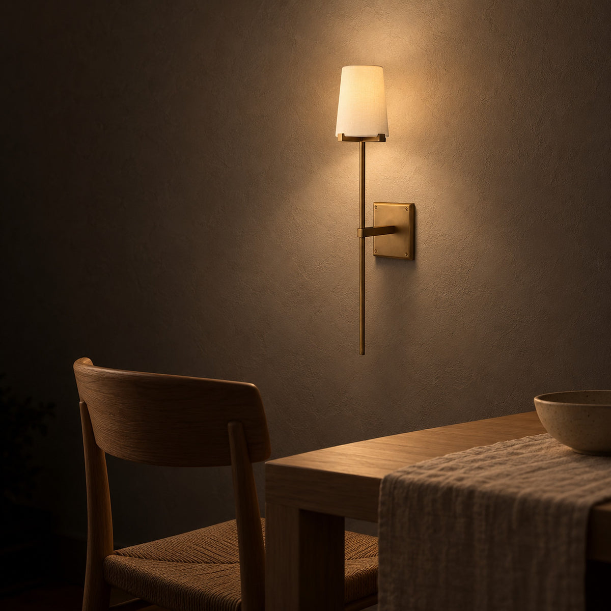 Savorel copper colored wall lamp with a fabric shade glowing over dining room furniture at night