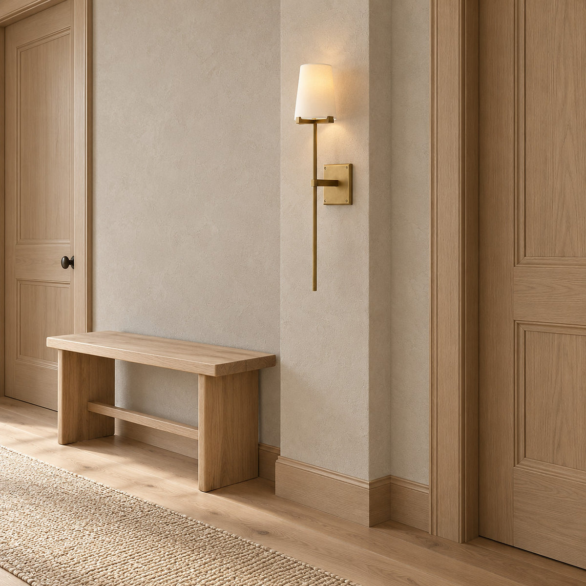 Savorel brass gold toned wall sconce with a lit cream shade between wooden doors beside a wooden bench