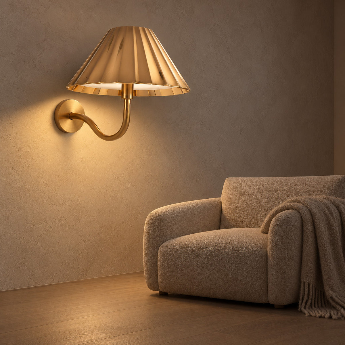 Selorna gold wall light glowing softly beside an armchair in a living room