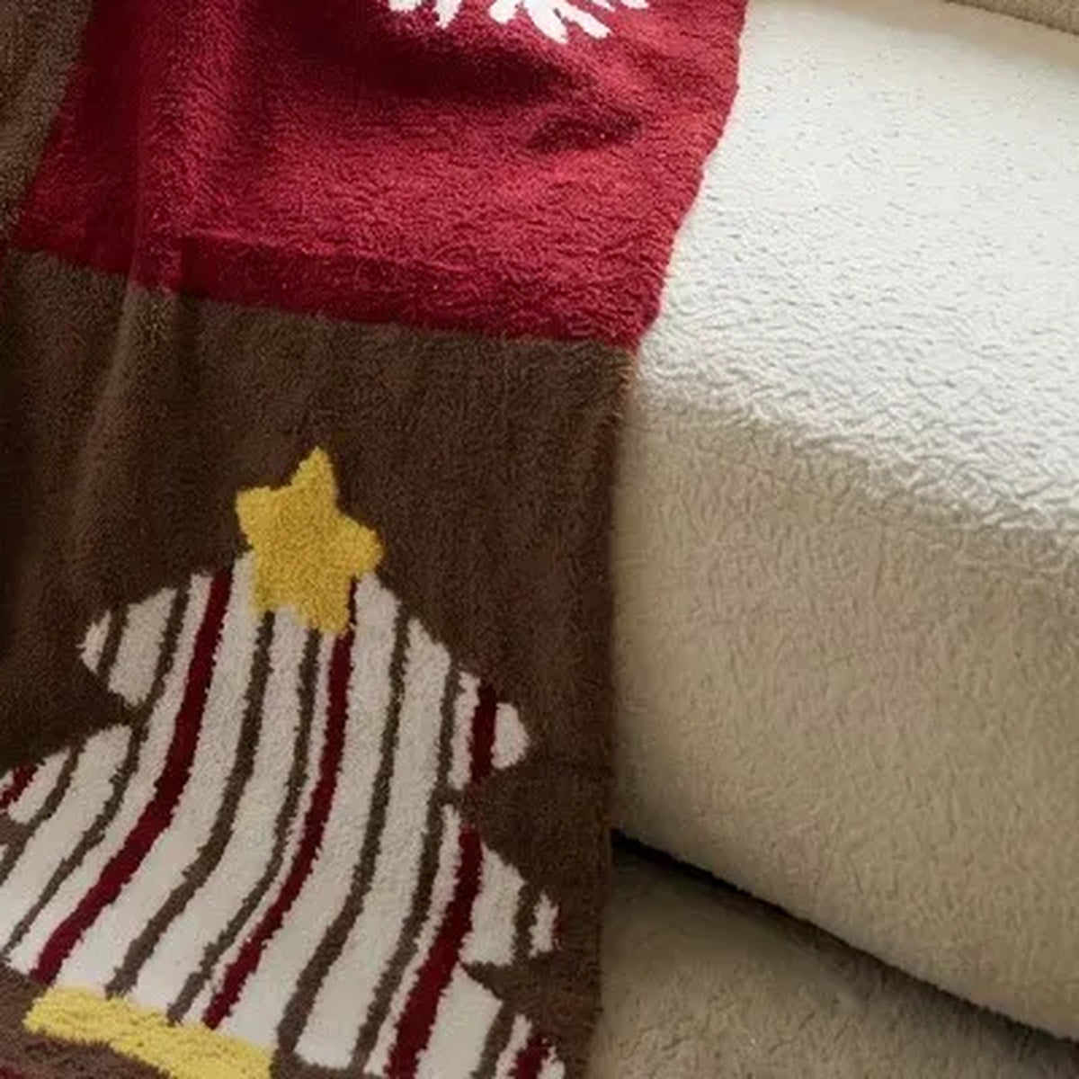 Senalio christmas fleece throw blanket draped over a cream sofa, showing a striped tree with a yellow star.