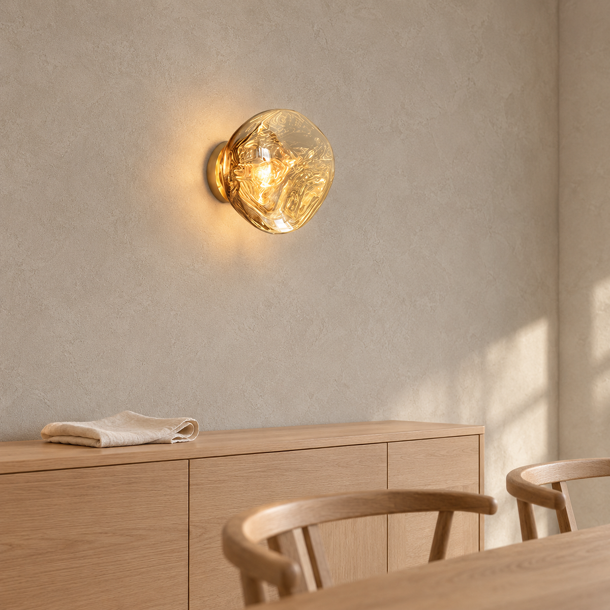 Sevalira gold wall lamp glowing on the wall above dining room furniture by day #color_gold