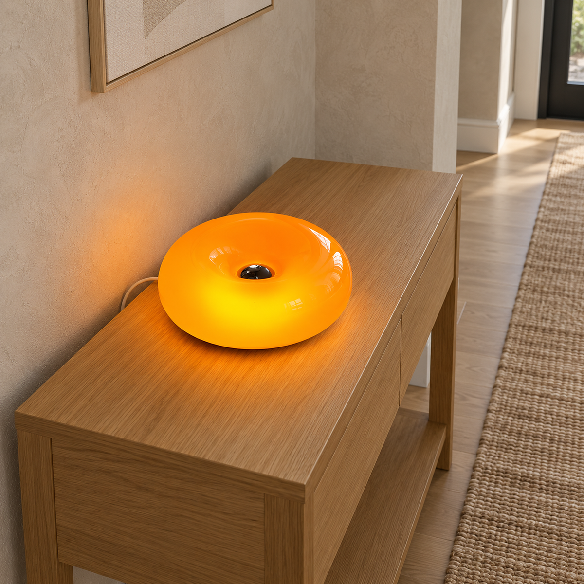 Siravel orange plug in wall lamp lit on a tabletop in the entryway with its power cord in view