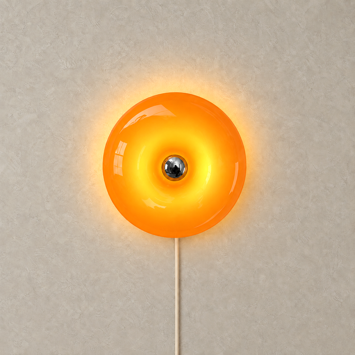 Siravel orange wall lamp lit from inside, its glass casting a warm halo onto the wall around the rim
