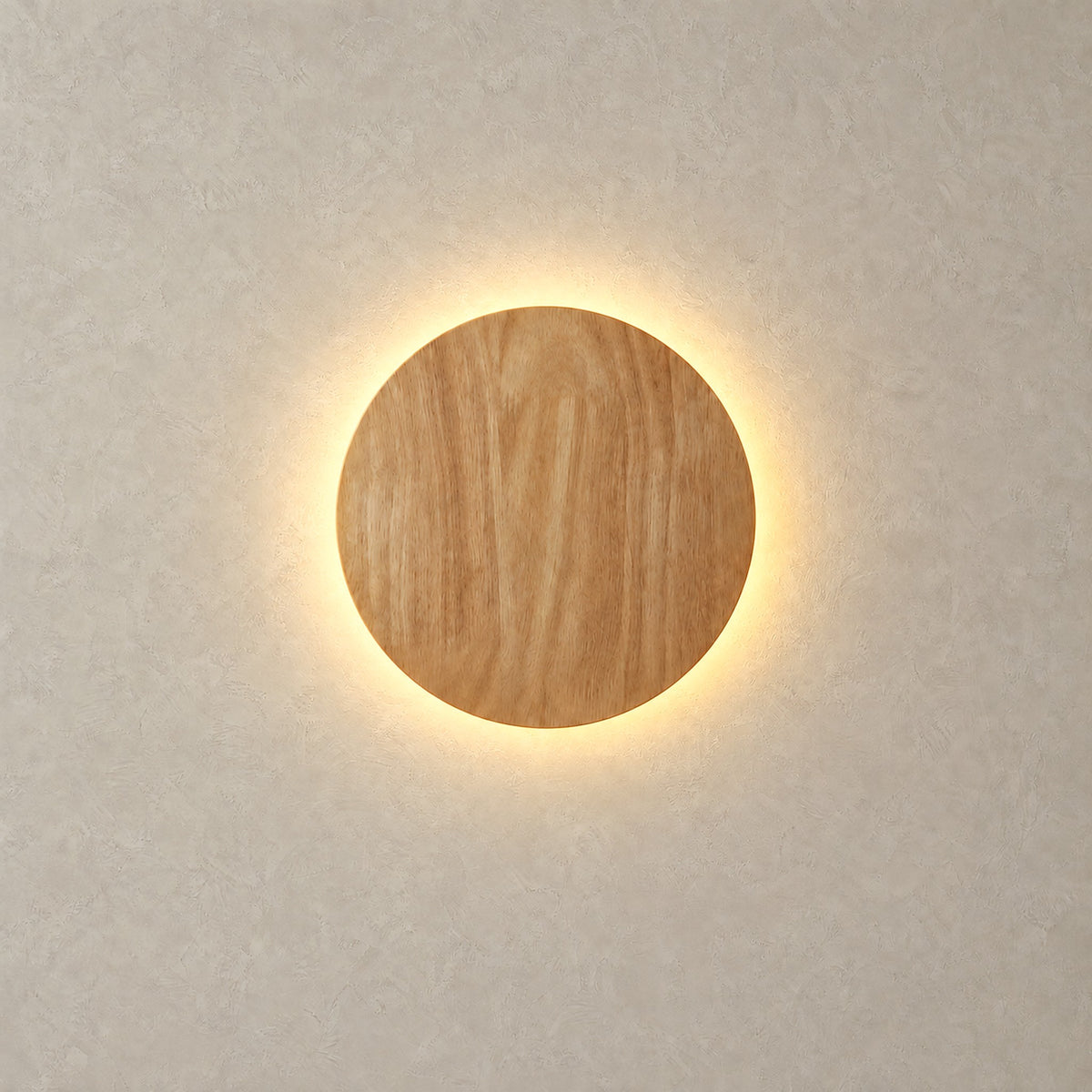 Sorivan light brown LED wall sconce lit with a warm halo around its round wood grain shade