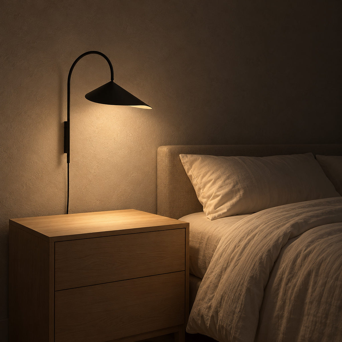 Talirsa black bedside wall light casting light beside a guest bed at night