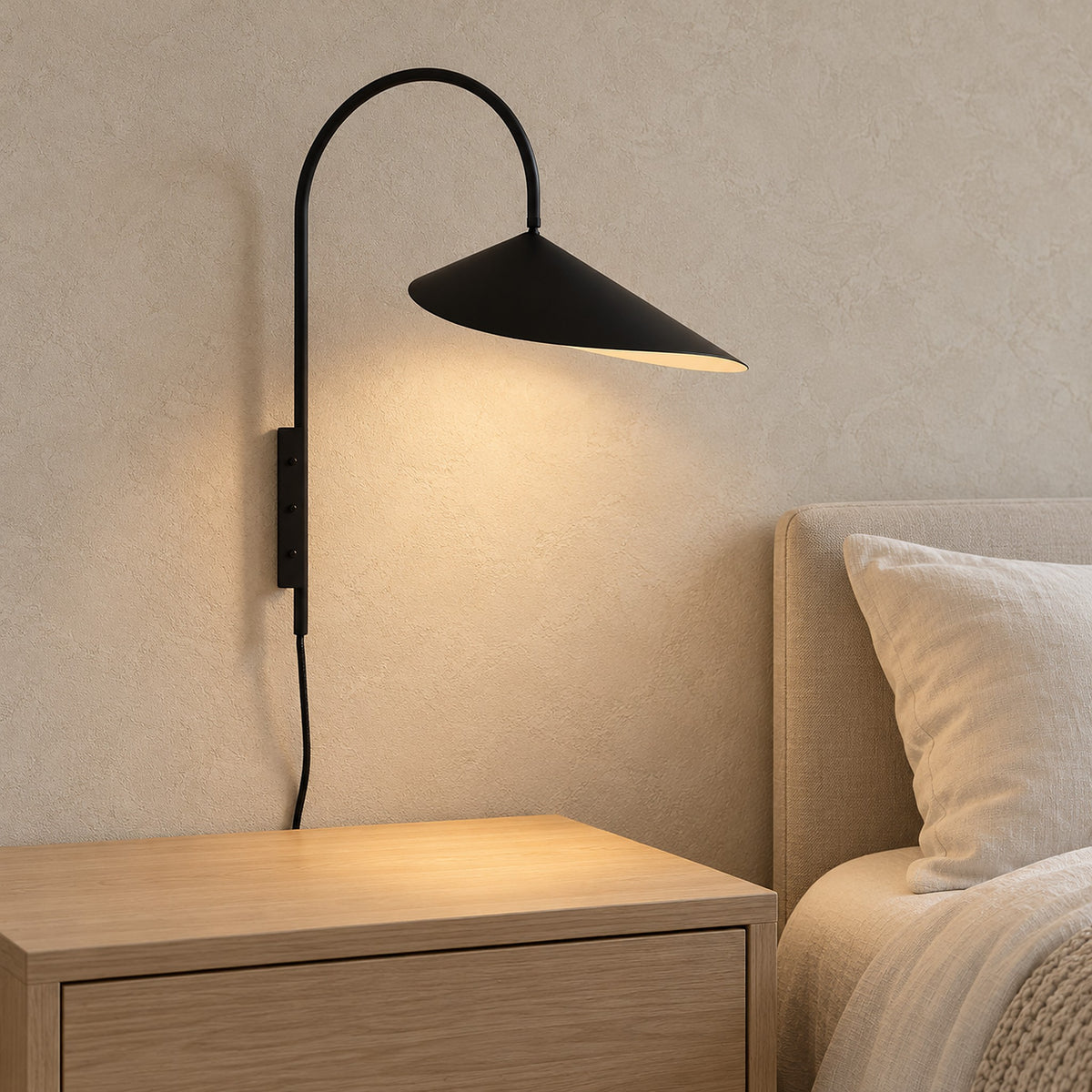 Talirsa black wall light glowing above a clear nightstand in a guest sleeping alcove