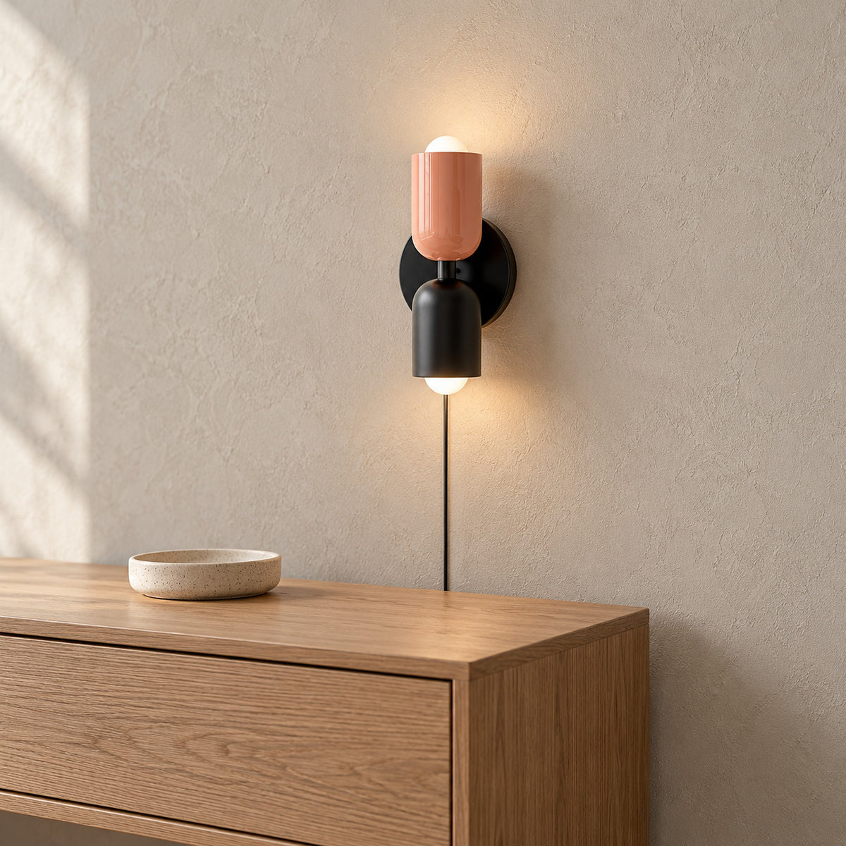 Talomi pink and black plug in wall sconce lit above the corner of an entryway console #color_pink & black