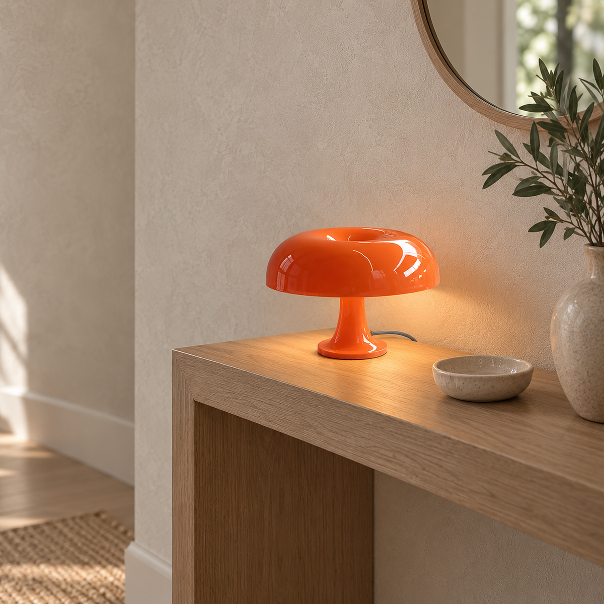 Tamolise mushroom table lamp in orange, lit with its resting base shown in an entryway