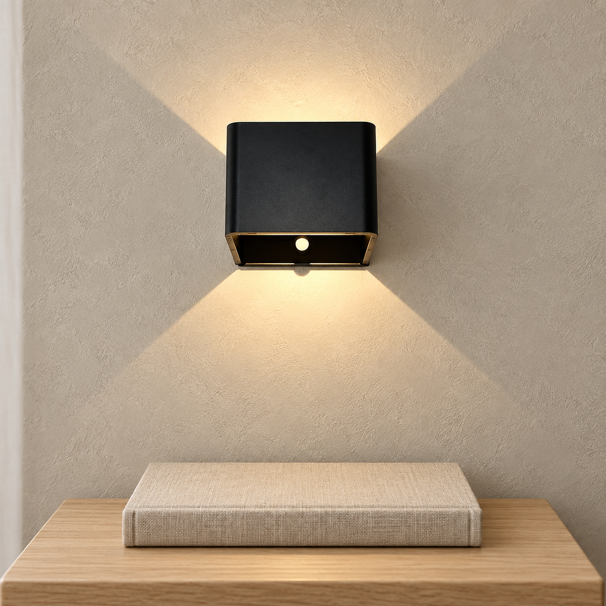 Tanelia black cordless wall lamp glowing above a side table with a closed book