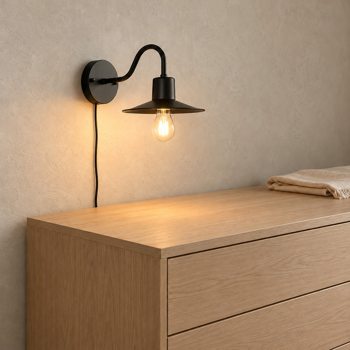 Tarelio black wall lamp with a 12 cm round backplate, lit above a dresser in a dressing room