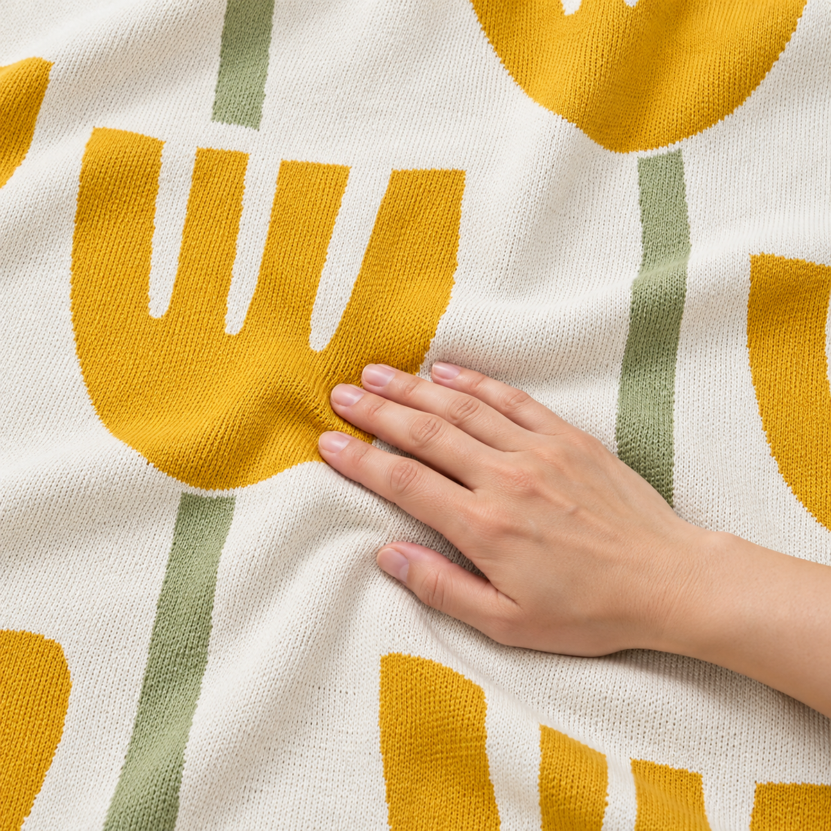 Taroveli yellow floral soft throw blanket with an adult hand smoothing the fine cotton knit