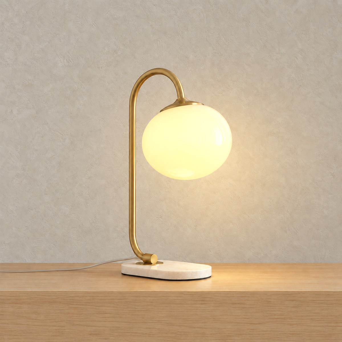 Taselvo gold and beige plug in table lamp lit up, its glass shade glowing on a plain backdrop