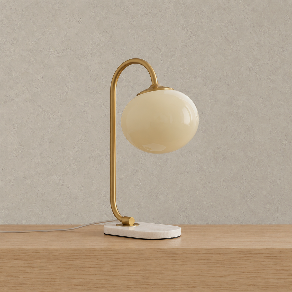 Taselvo gold and beige plug in table lamp shown unlit, glass shade hanging from a curved pole over a white base