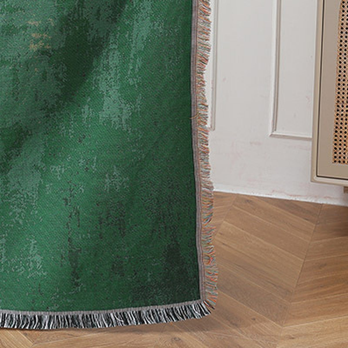 Timarno woven sheep throw blanket hanging beside a white wall, showing a green corner and fringe above a wood floor.