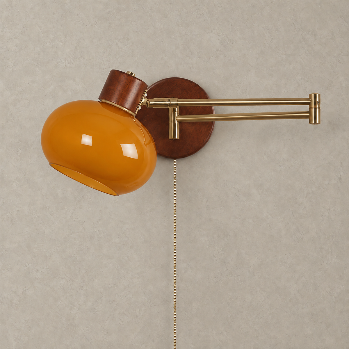 Tolvaren amber swing arm wall sconce unlit on plaster, with a gold colored arm and dark walnut wall plate