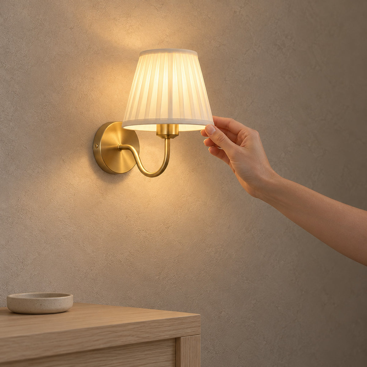 Tomirel gold battery operated wall sconce lit on a clear stretch of hallway plaster