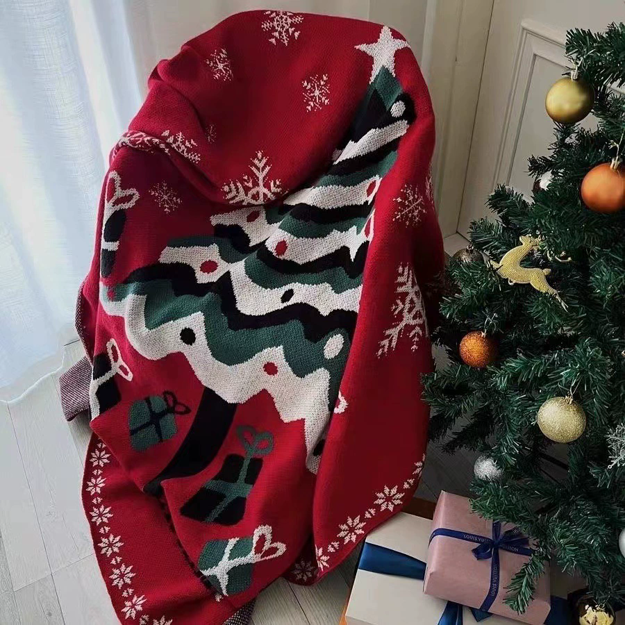 Velimoro red christmas knit throw blanket draped over a chair, showing tree and snowflake patterns beside a Christmas tree