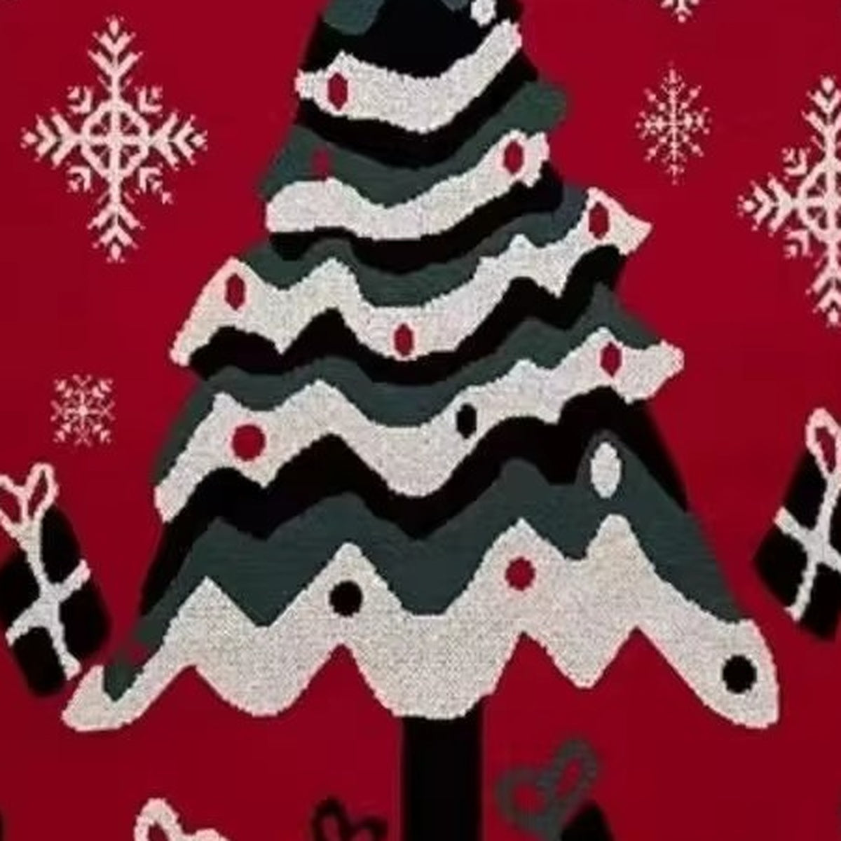 Close up of Velimoro christmas knit throw blanket showing a decorated tree and white snowflakes on red knit fabric.