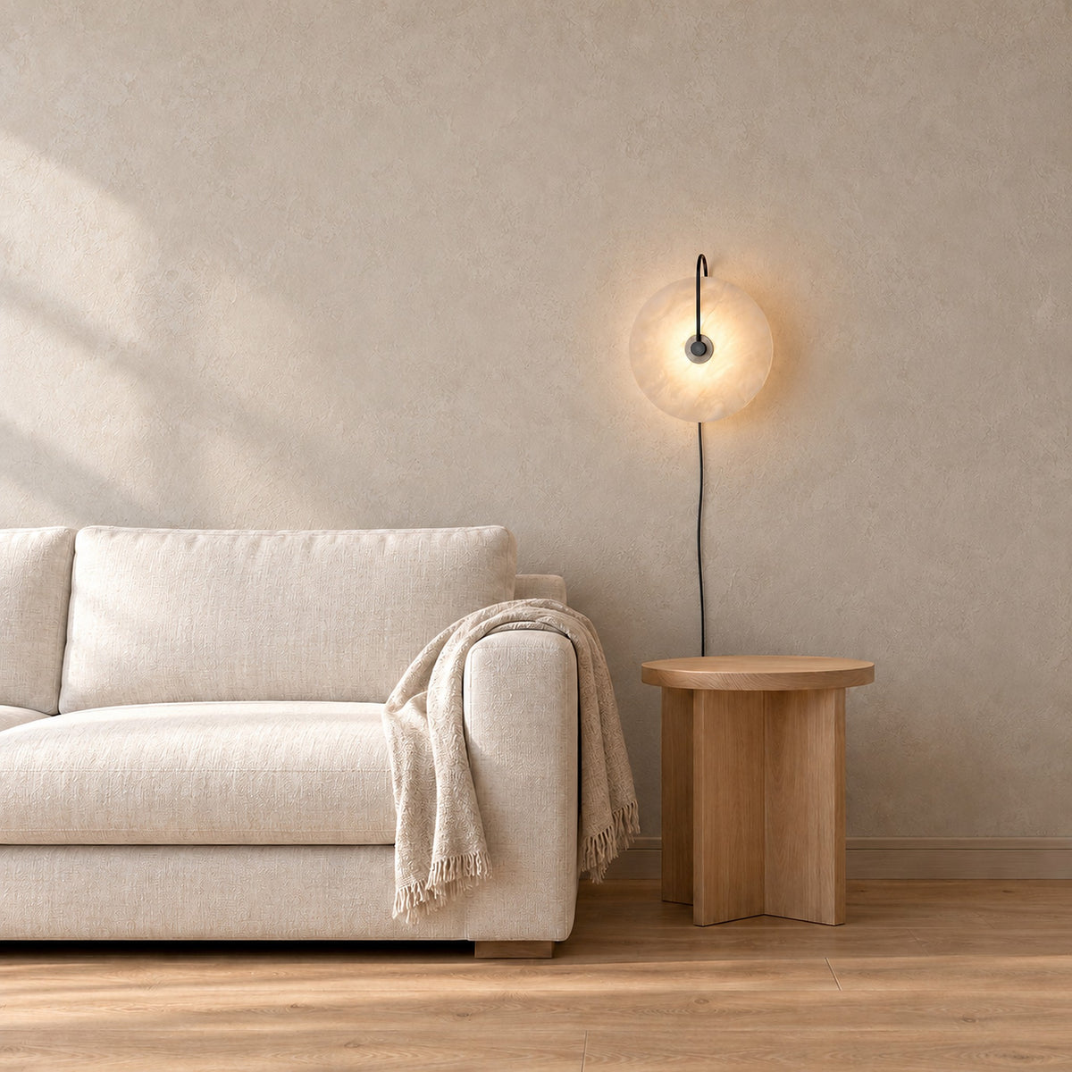 Velirsa black wall light glowing beside an oatmeal sofa in a bright living room