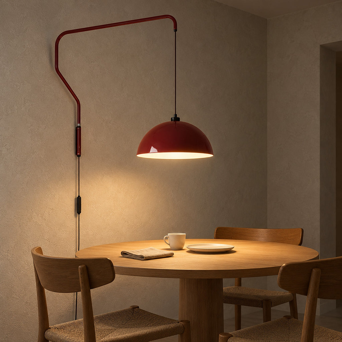 Velisano dark red plug in wall sconce, its wall arm suspending a glowing dome shade